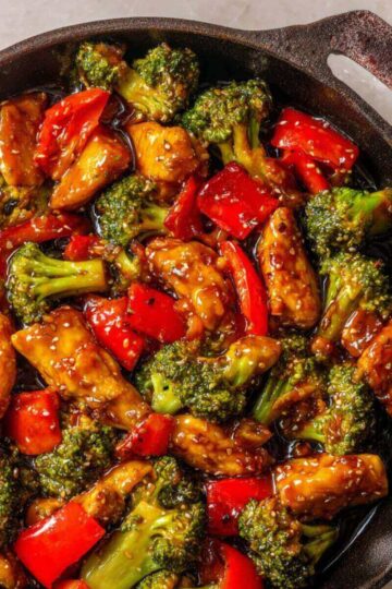 30 Minute Chicken Stir Fry with broccoli and red bell peppers in a savory sauce, cooked in a skillet.