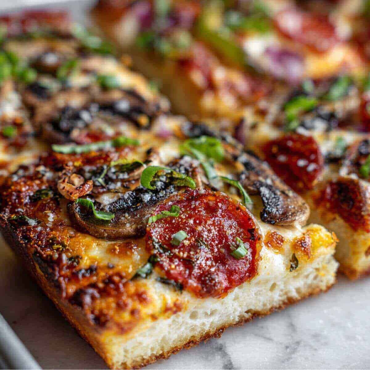 bread pizza topped with pepperoni, mushrooms, melted cheese