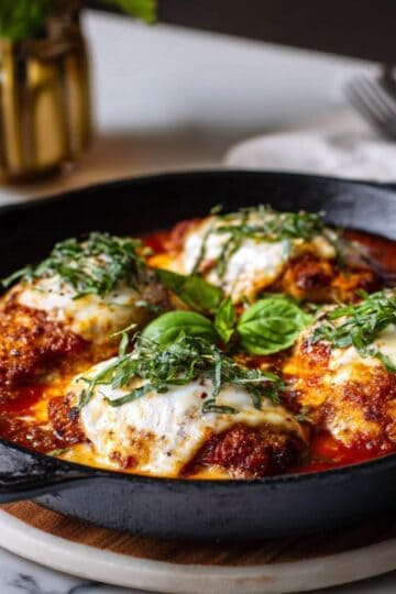 Skillet chicken parmesan topped with melted mozzarella and fresh basil in marinara sauce.