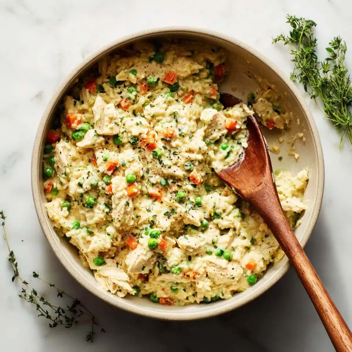 Creamy Freezer Chicken Casserole Recipe mixture in a bowl with chicken, peas, carrots, and rice stirred.
