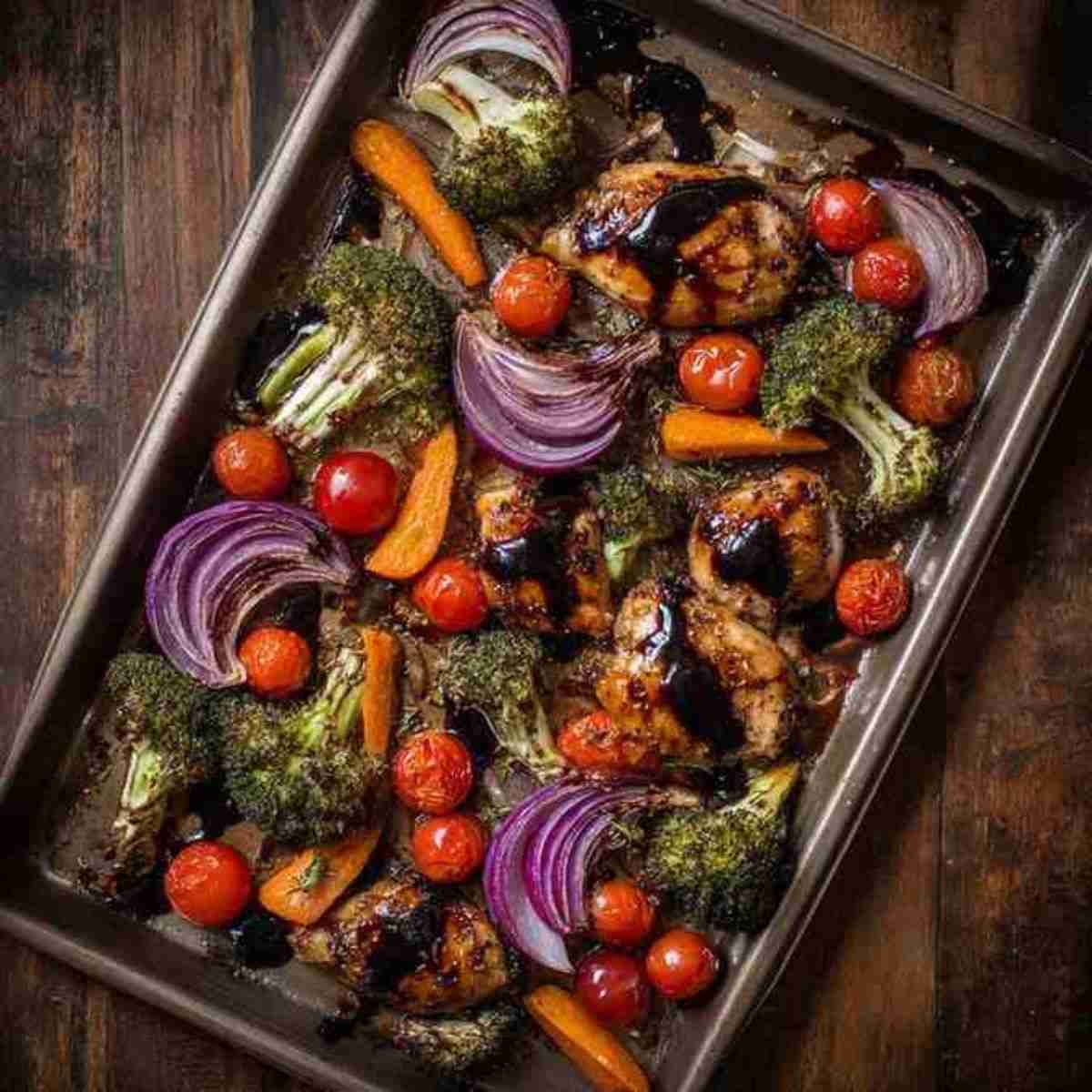 Sheet pan balsamic chicken with roasted broccoli, carrots, cherry tomatoes, and red onions.
