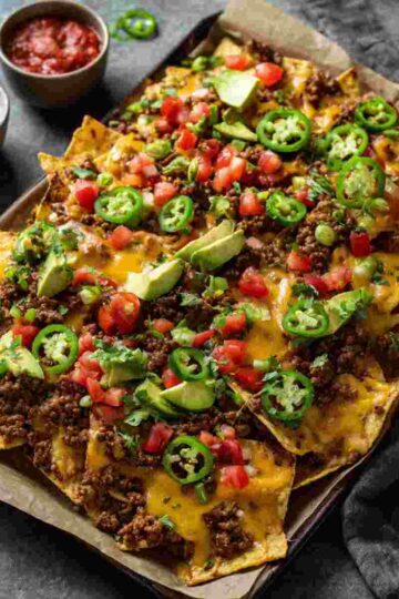 Ground beef nachos on a sheet pan with melted cheese and fresh toppings