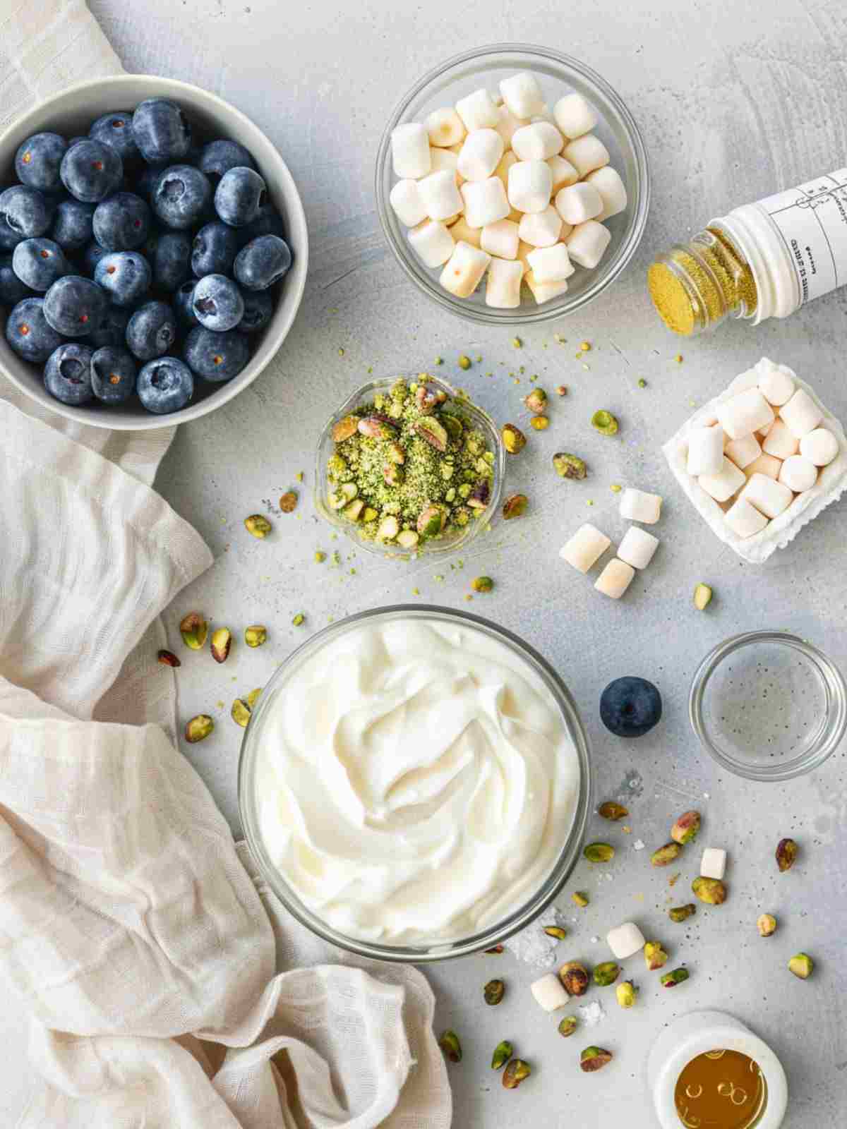 Ingredients for blueberry pistachio salad including blueberries pistachio pudding Greek yogurt pineapple marshmallows and pistachios
