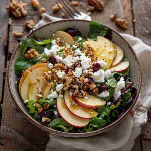 Honeycrisp apple feta salad with mixed greens, cranberries, and walnuts in a ceramic bowl